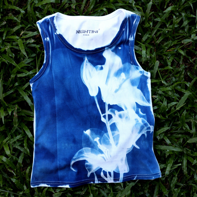 Blaues Lily Crop Top mit weißem Lilienprint, flach auf Gras fotografiert