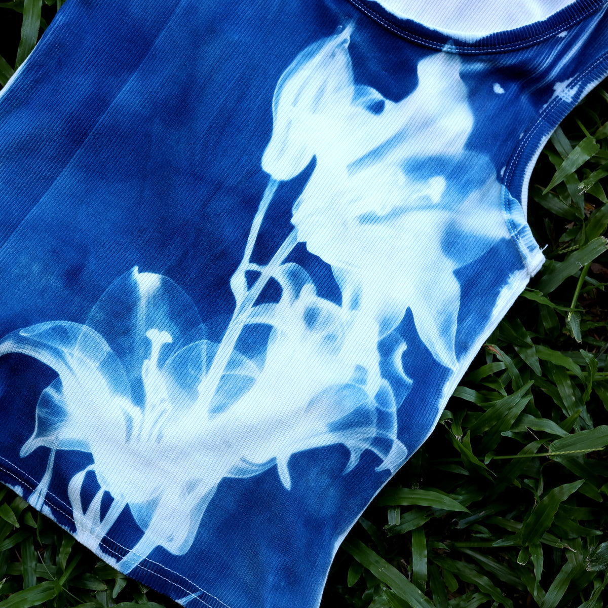 Detailansicht des weißen Lilienprints und der gerippten Stoffstruktur des blauen Crop Tops