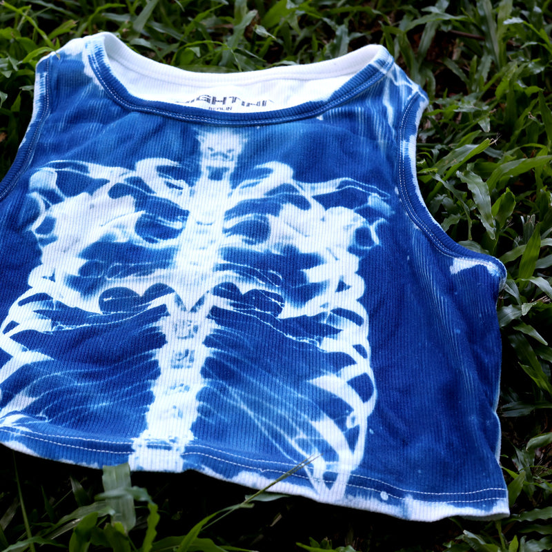 Detailansicht des weißen Brustkorbmotivs und der Stoffstruktur auf dem blauen X-Ray Crop Top